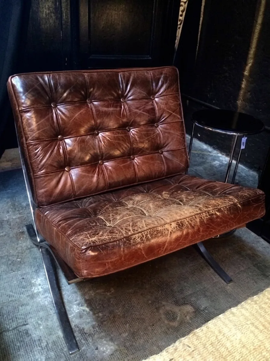 Heavily cracked, worn button-tufted lounge chair before restoration
